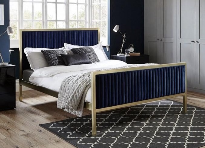 dark blue bedroom with velvet blue bed and geometric rug 