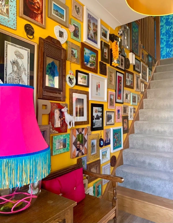 bright yellow hallway with lots of artwork going up the stairs