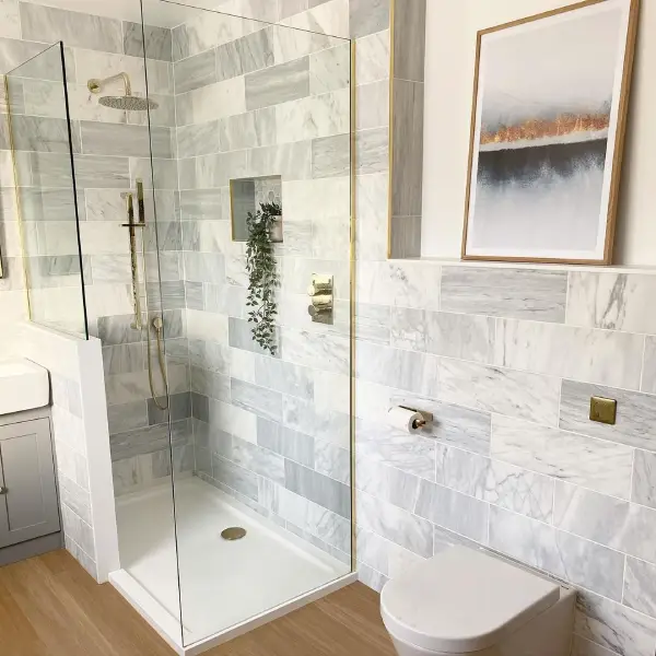 Gold bathroom fixtures in a light grey bathroom