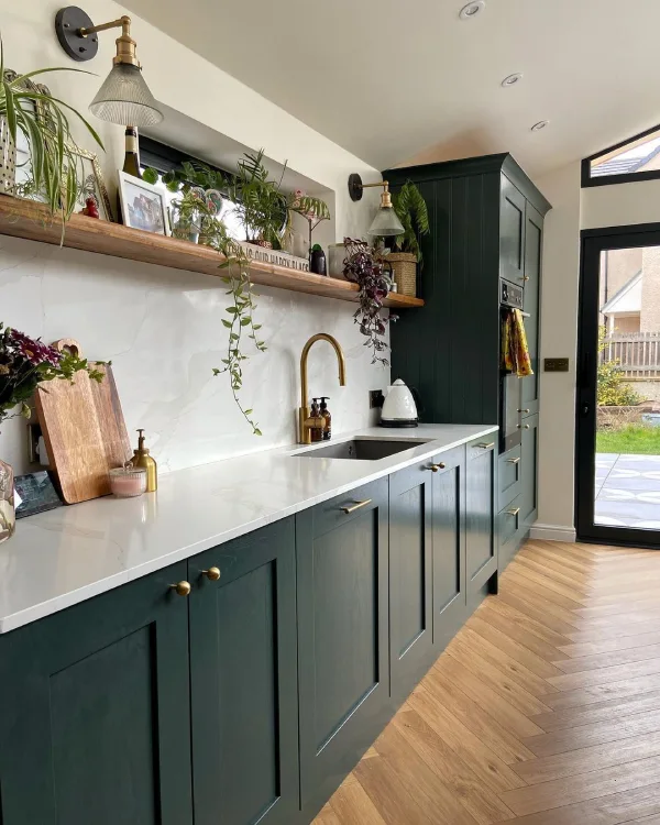 Dark green cabinets and gold fixtures in a white kitchen