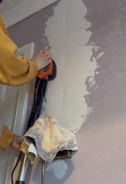 sanding down plaster on a wall